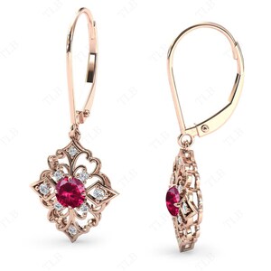May include: A pair of rose gold earrings with a red ruby gemstone and clear diamonds set in a delicate filigree design. The earrings have a leverback closure.