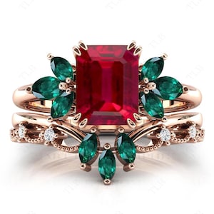 以下が含まれることがあります： ローズゴールドのリングは、大きなエメラルドカットのルビーを、より小さなエメラルドカットの緑色の宝石で囲んでいます。リングは、繊細なバンドに花柄と小さなダイヤモンドをあしらった、マッチングセットの一部です。
