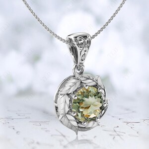 Pu&ograve; includere: Una collana d'argento con un ciondolo di pietra preziosa verde circondato da dettagli a forma di foglie.