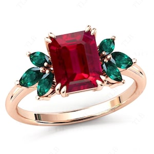 Op de afbeelding: Een ring van roségoud met een grote smaragd geslepen robijn, omringd door kleinere smaragd geslepen groene edelstenen.