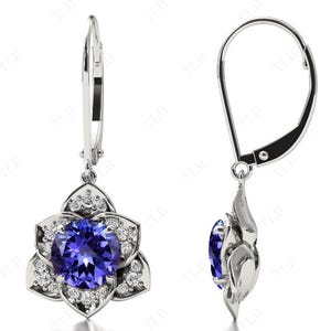 Pu&ograve; includere: Un paio di orecchini pendenti in argento con una pietra preziosa blu circondata da pietre bianche pi&ugrave; piccole a forma di fiore.