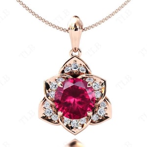 May include: A rose gold pendant necklace featuring a red gemstone surrounded by smaller white gemstones. The pendant is shaped like a flower with five petals.