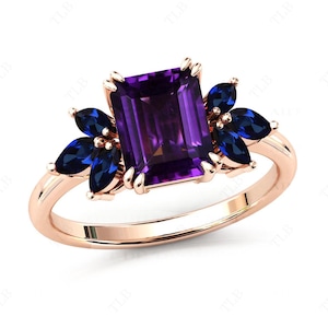 May include: A rose gold ring featuring a large, emerald-cut amethyst gemstone surrounded by smaller, marquise-shaped sapphire gemstones.
