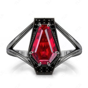 Könnte beinhalten: Ein schwarzer Ring im gotischen Stil mit einem großen, roten, facettierten Edelstein, der in einer Sargformfassung sitzt.
