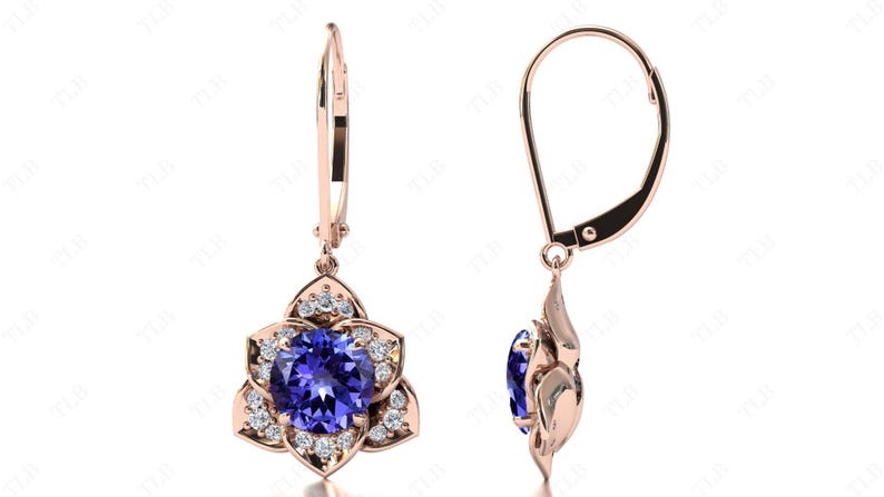 Pu&ograve; includere: Orecchini pendenti in oro rosa con una pietra preziosa blu circondata da pietre bianche pi&ugrave; piccole. Gli orecchini hanno una chiusura a leva.
