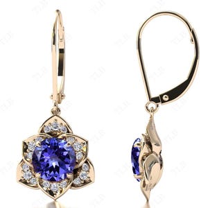 Pu&ograve; includere: Un paio di orecchini pendenti in oro con una pietra preziosa blu circondata da pietre bianche pi&ugrave; piccole a forma di fiore.