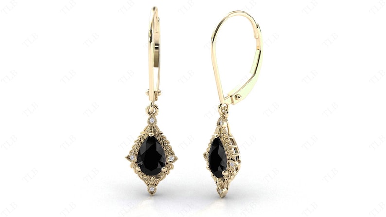 May include: A pair of gold dangle earrings with a pear-shaped black gemstone surrounded by smaller white gemstones.
