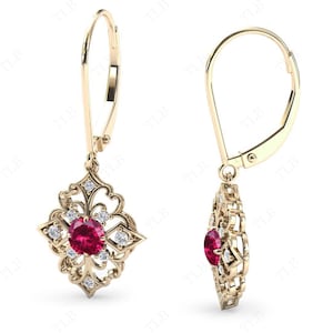 May include: Gold dangle earrings with a red gemstone surrounded by smaller white gemstones in a filigree design.