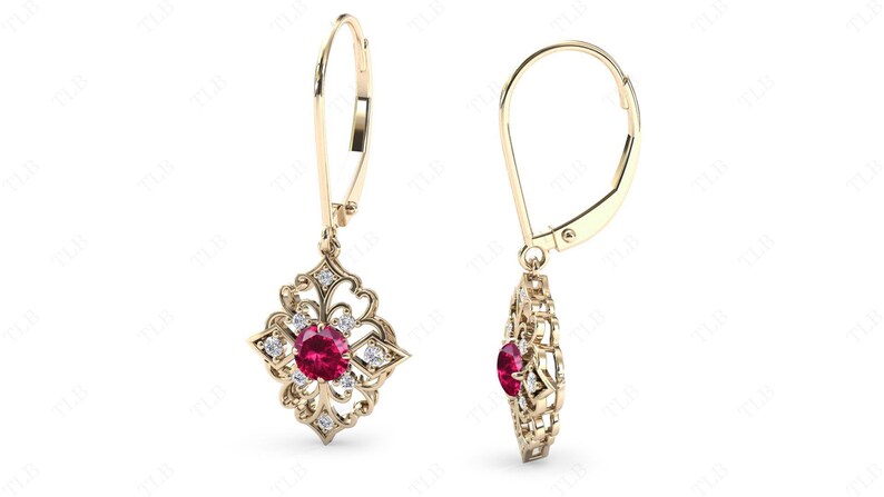May include: Gold dangle earrings with a red gemstone surrounded by smaller white gemstones in a filigree design.