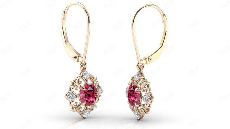 May include: A pair of gold dangle earrings with a red gemstone and small white gemstones in a filigree design.