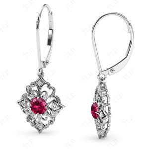 May include: A pair of silver dangle earrings with a red gemstone surrounded by smaller white gemstones in a floral design.