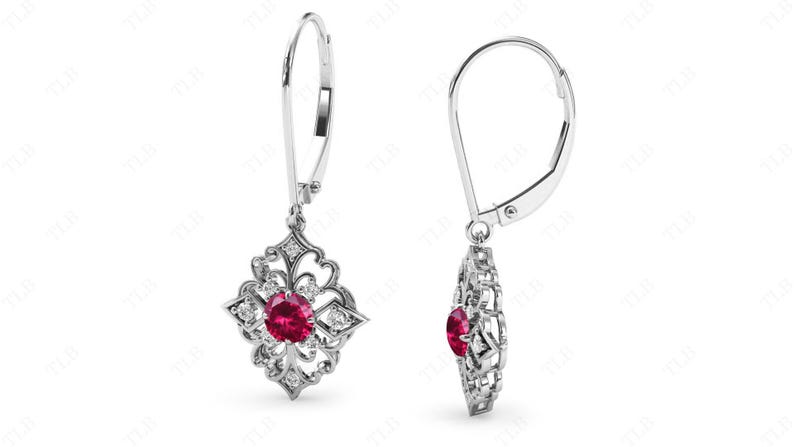 May include: A pair of silver dangle earrings with a red gemstone surrounded by smaller white gemstones in a floral design.