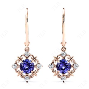 Puede incluir: Un par de pendientes colgantes de oro rosa con una piedra preciosa redonda de color p&uacute;rpura rodeada de piedras preciosas transparentes m&aacute;s peque&ntilde;as en un dise&ntilde;o de filigrana.
