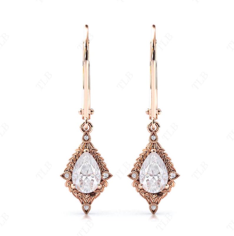 Puede incluir: Un par de pendientes colgantes de oro rosa con piedras preciosas transparentes en forma de pera engastadas en un dise&ntilde;o delicado y ornamentado.