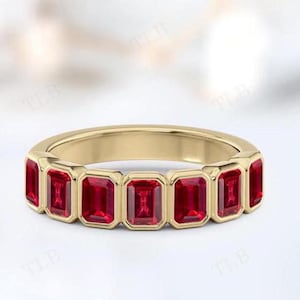 Op de afbeelding: Een gouden ring met een rij rode smaragd geslepen edelstenen.