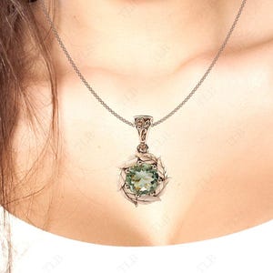 Pu&ograve; includere: Una collana con catena d'argento con un ciondolo di pietra preziosa verde. Il ciondolo &egrave; circondato da un delicato design in argento.