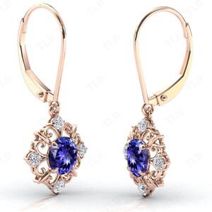 Puede incluir: Un par de pendientes colgantes de oro rosa con una piedra preciosa azul rodeada de piedras blancas m&aacute;s peque&ntilde;as en un dise&ntilde;o de filigrana.