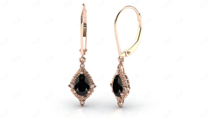 May include: A pair of rose gold dangle earrings with a pear-shaped black gemstone surrounded by smaller white gemstones. The earrings have a leverback closure.