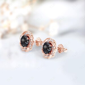 Peut inclure: Une paire de boucles d'oreilles en or rose avec une pierre pr&eacute;cieuse noire entour&eacute;e d'un halo de petites pierres blanches.
