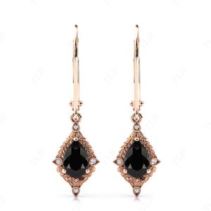 May include: A pair of rose gold dangle earrings with black pear-shaped gemstones set in a delicate floral design. The earrings feature a hoop design and are accented with small clear gemstones.