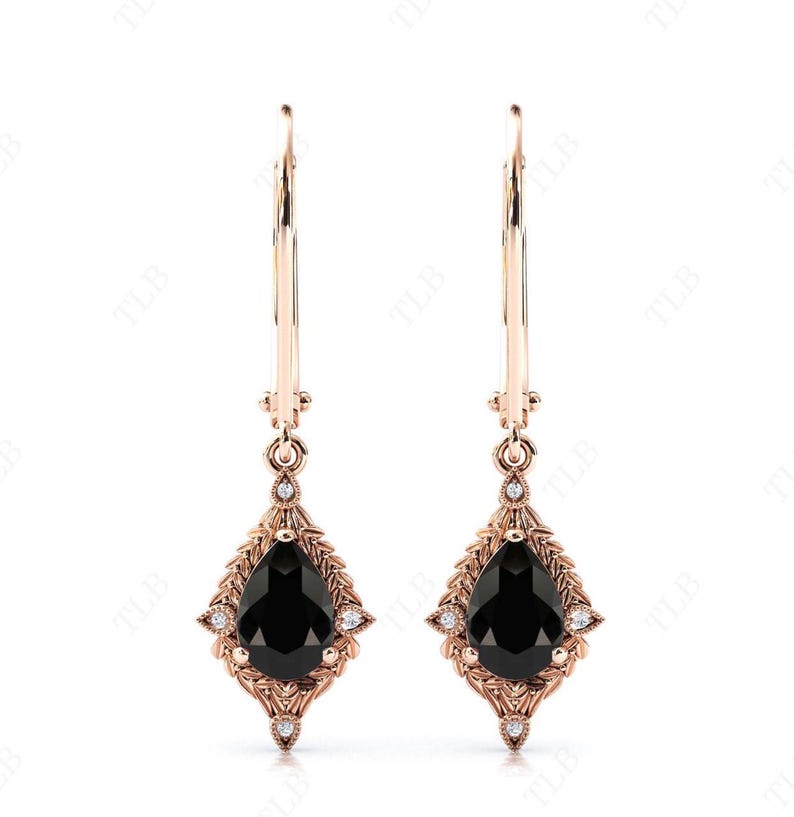 May include: A pair of rose gold dangle earrings with black pear-shaped gemstones set in a delicate floral design. The earrings feature a hoop design and are accented with small clear gemstones.