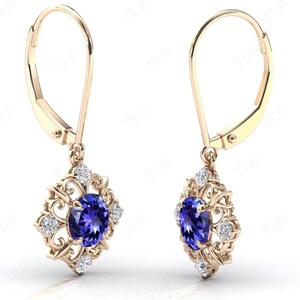 Puede incluir: Un par de pendientes de oro con una piedra preciosa azul y piedras blancas m&aacute;s peque&ntilde;as engastadas en un dise&ntilde;o de filigrana.