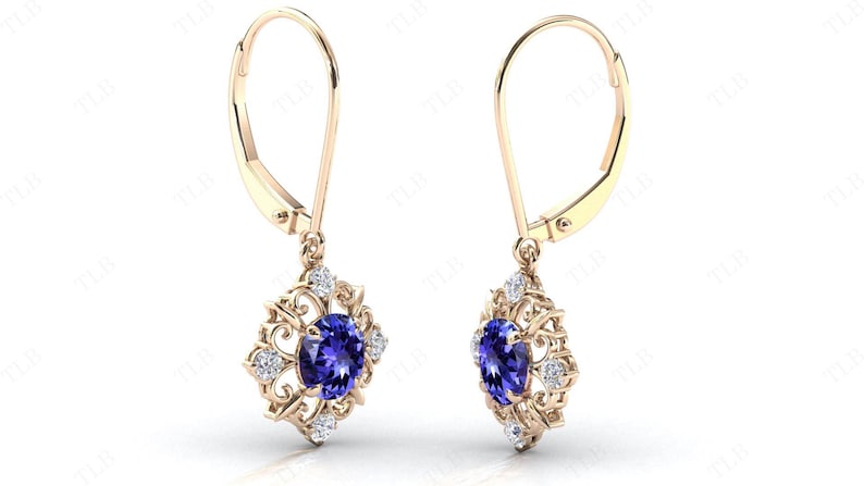 Puede incluir: Un par de pendientes de oro con una piedra preciosa azul y piedras blancas m&aacute;s peque&ntilde;as engastadas en un dise&ntilde;o de filigrana.