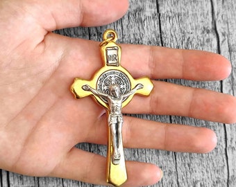 May include: A gold-colored metal crucifix with a silver-colored Jesus figure. The crucifix has a round medallion with the inscription "INRI" and other religious symbols.