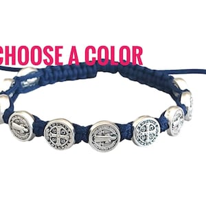 May include: A navy blue bracelet with silver-colored circular charms. The charms are evenly spaced along the braided cord. The text "CHOOSE A COLOR" is in pink above the bracelet.