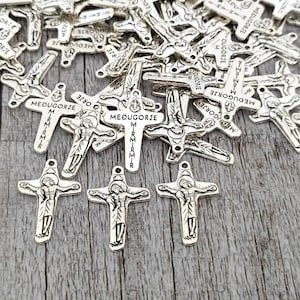 Peut inclure: Un tas de breloques en forme de croix en métal argenté avec l'inscription "Medjugorje" et "Mir Mir Mir".