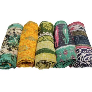 May include: Five rolled kantha quilts in various colours. Each quilt features unique patterns and colours, including teal, yellow, green, black, and red. The quilts are made of soft, textured fabric.