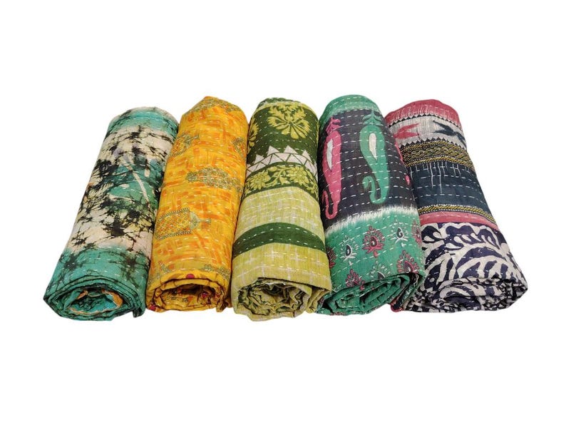 May include: Five rolled kantha quilts in various colours. Each quilt features unique patterns and colours, including teal, yellow, green, black, and red. The quilts are made of soft, textured fabric.