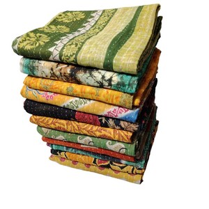 May include: A pile of vibrant, patterned quilts. The quilts display diverse designs, including floral and geometric patterns, in shades of green, yellow, orange, and blue. The quilts are neatly folded and stacked, highlighting the range of colours and designs.