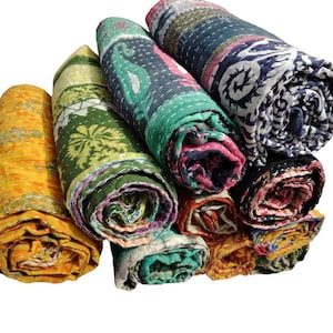 May include: A collection of rolled kantha quilts in various colours and patterns. The quilts feature designs in yellow, green, teal, pink, and navy. Each quilt is tightly rolled, highlighting the detailed stitching and design.