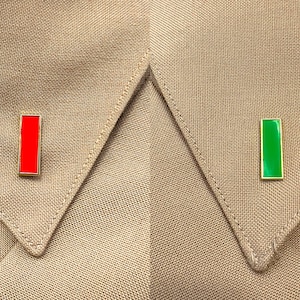 May include: Two rectangular pins on a brown fabric background. The pin on the left is red and the pin on the right is green.