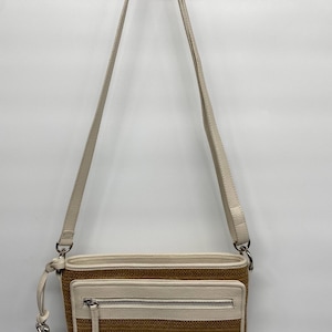 May include: A rectangular crossbody bag featuring a textured tan woven body with cream-colored leather trim. The bag includes an adjustable cream shoulder strap, a front zippered pocket with a silver-tone metal pull, and silver-tone hardware accents.