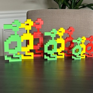 May include: A set of five colorful toy robots made of plastic blocks. The robots are arranged in order of size, with the largest robot on the left and the smallest robot on the right. The robots are green, yellow, and red.