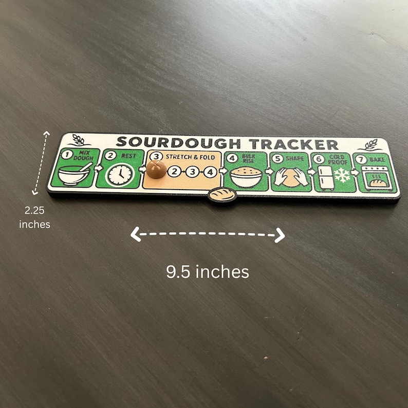 Puede incluir: Un tablero de seguimiento de masa madre rectangular que mide 5,7 cm por 24,1 cm. El tablero presenta siete pasos numerados para hacer pan: Mix Dough, Rest, Stretch & Fold, Bulk Rise, Shape, Cold Proof y Bake, con un peque&ntilde;o marcador en forma de pan.