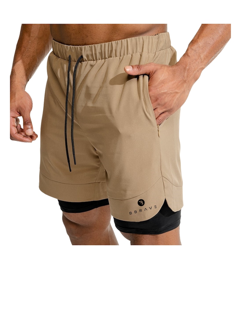 May include: Tan athletic shorts with a black inner liner. The shorts have a drawstring waistband and a zippered pocket on the right side. The shorts have the word "BBRAVE" printed on the left leg.