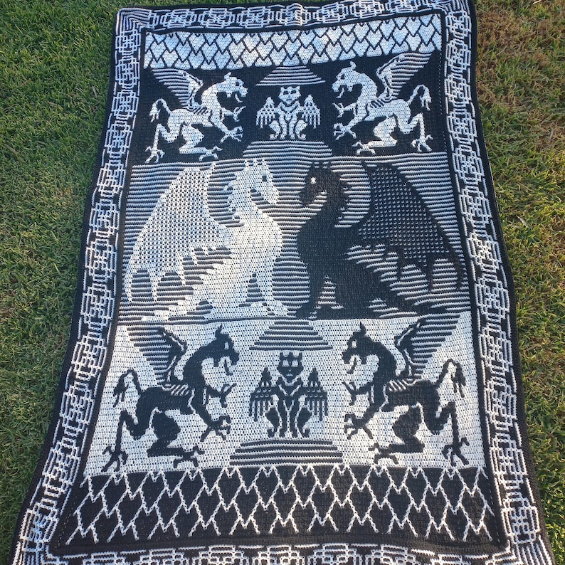 May include: Black and white crocheted throw blanket with a dragon design. The blanket features a repeating pattern of dragons, hearts, and geometric shapes.