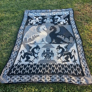 May include: Black and white crocheted throw blanket with a design of dragons and a repeating pattern of hearts and squares.