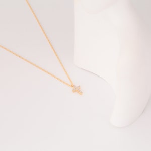 May include: A gold chain necklace with a small, sparkling cross pendant.