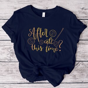 A picture showing a layed out Bella Canvas Unisex 3001 t-shirt in navy color with the words after all this time; in cursive gold lettering and with wizard symbols.