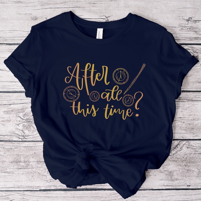 A picture showing a layed out Bella Canvas Unisex 3001 t-shirt in navy color with the words after all this time; in cursive gold lettering and with wizard symbols.