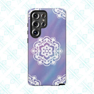 May include: A smartphone case featuring a purple and blue galaxy-style background with a white floral mandala design. The case has a black camera module and a black border. The design is repeated in the corners.