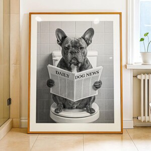 May include: Framed black and white print of a French Bulldog sitting on a toilet, reading a newspaper titled "DAILY DOG NEWS". The artwork is displayed in a bathroom setting with a neutral color palette.