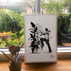 May include: A framed black and white ink drawing of a person climbing a ladder to reach a plant. The drawing is on white paper with a white frame. The drawing is signed in the bottom right corner.