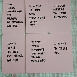 May include: Six rectangular cards with black handwritten text on a light pink background. The cards contain phrases like "You have awakened hot flame of passion in me" and "I want to taste you."