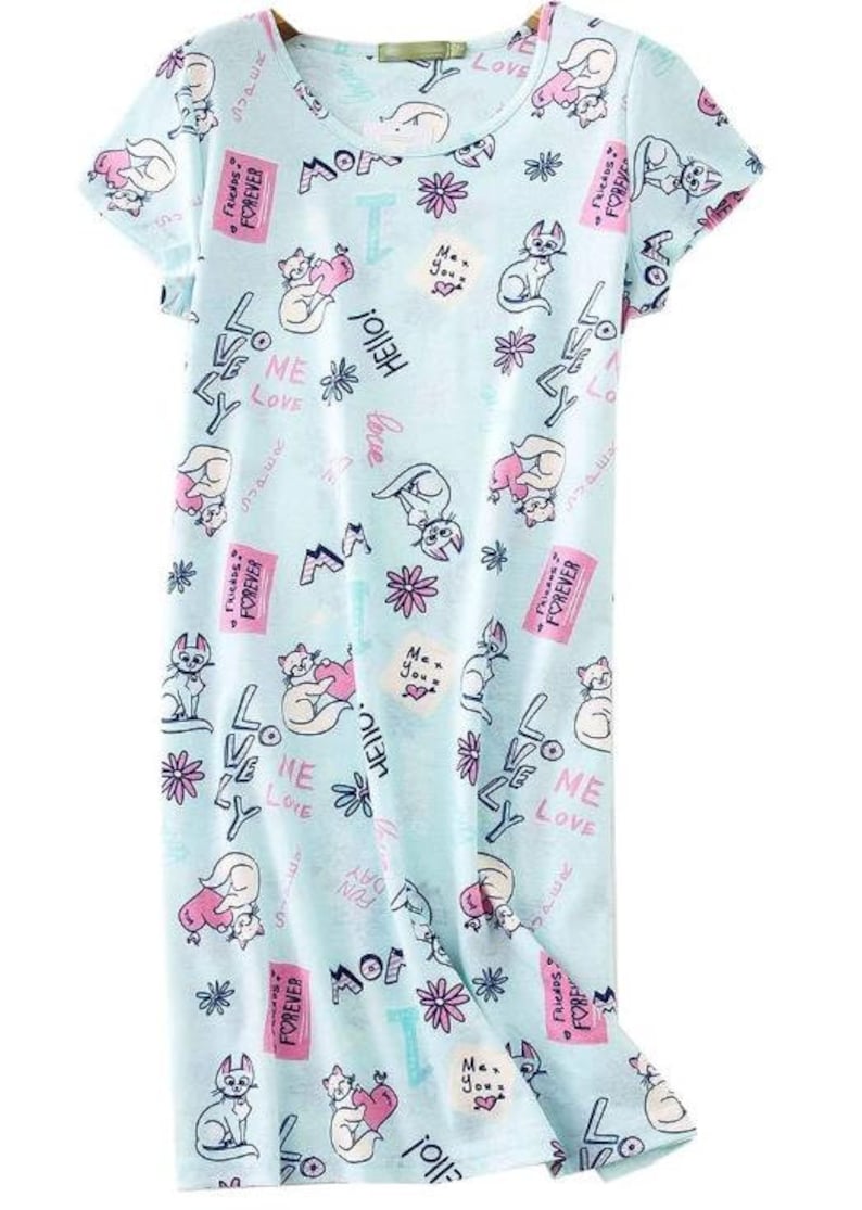 May include: Light blue short-sleeve nightgown with a repeating pattern of cartoon cats, flowers, and text. The text includes words like "Love", "Hello", and "Forever". The nightgown has a scoop neck and a relaxed fit.