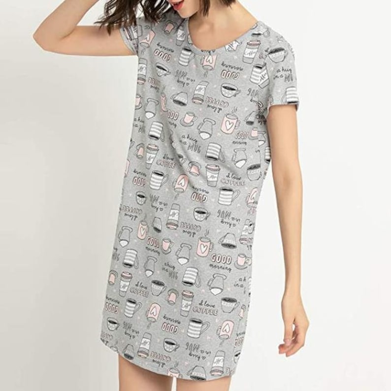 May include: Gray short-sleeve sleep shirt with a pattern of coffee cups, mugs, and the phrases "I love coffee", "Good morning", and "a hug in a mug". The sleep shirt has a scoop neck.